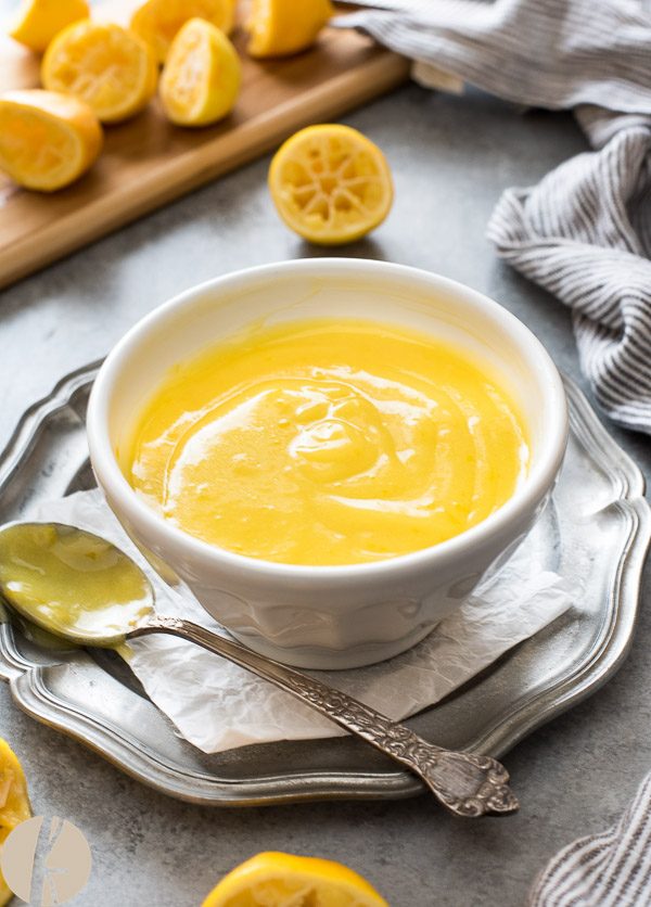 Lemon curd in white bowl with spoon alongside