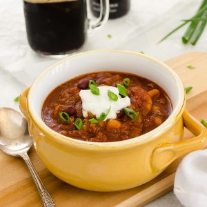 Guinness Beef Chili in a bowl with sour cream and scallions on top