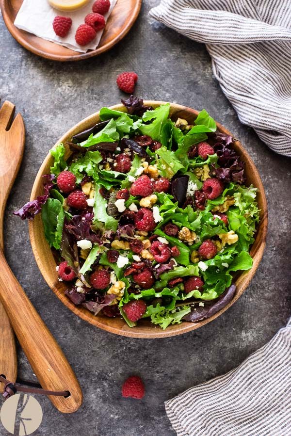 raspberry salad with baby lettuce in teak bowl with servers