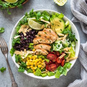 Santa fe chicken salad in white bowl with fork and lime