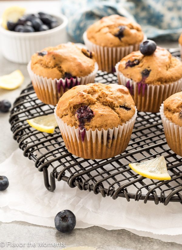 front shot of blueberry lemon muffins on wire rack with lemon slices