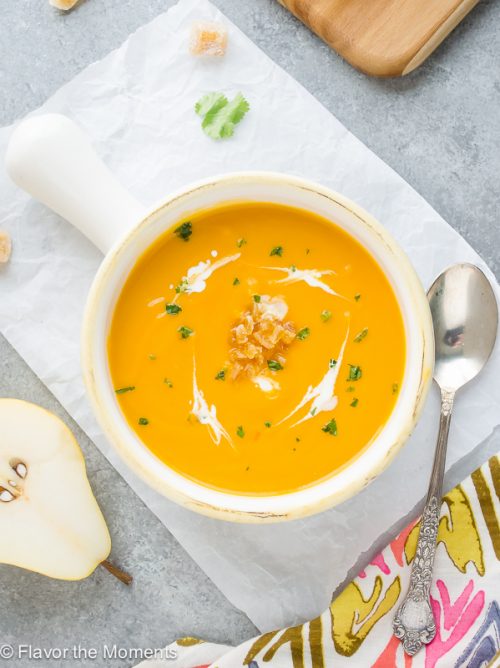 Bowl of butternut squash pear soup with candied ginger and creme fraiche on top