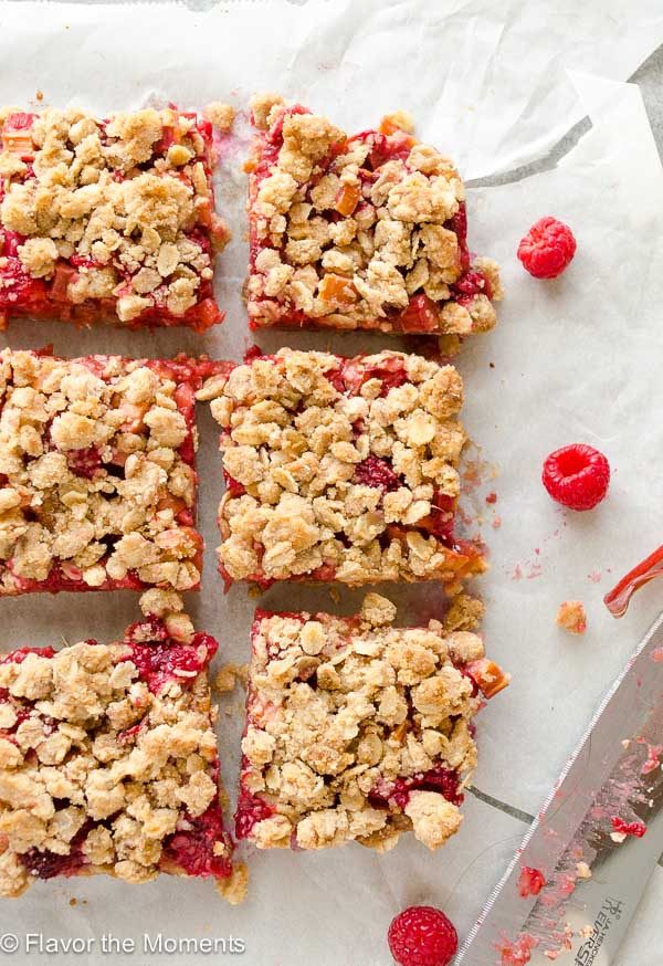 Raspberry rhubarb bars cut into square on parchment