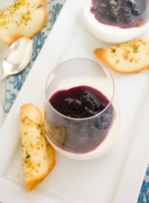 Blueberry panna cotta in wine glass with pistachio tuile