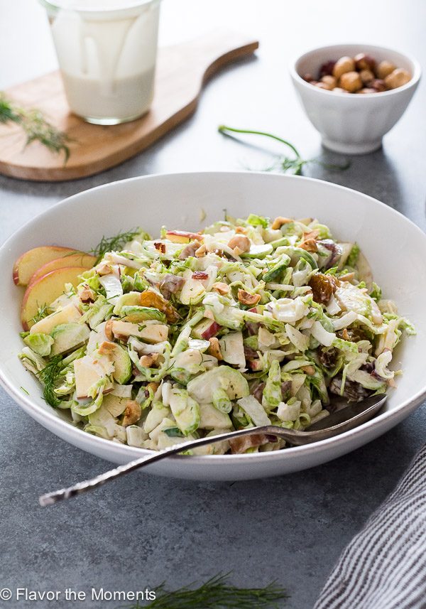 Shaved brussels sprout salad in a white bowl with apples