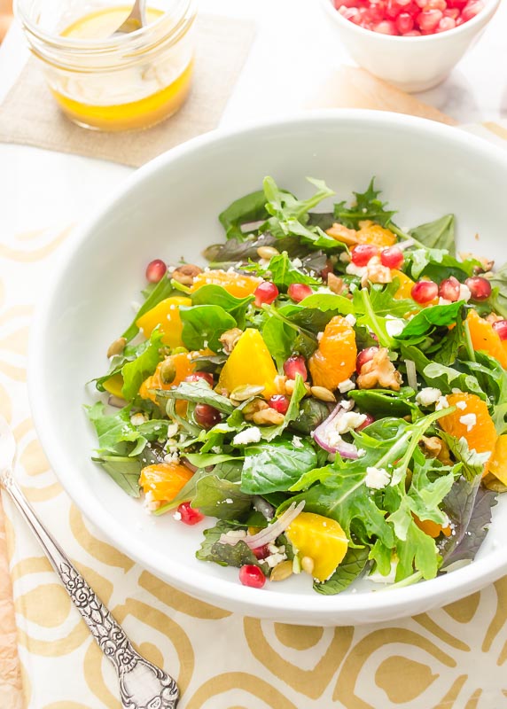 Golden beet and orange salad in white bowl with pomegranate on top