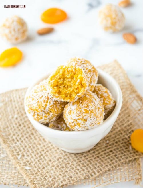 Apricot almond coconut energy balls in a bowl with bite out of one