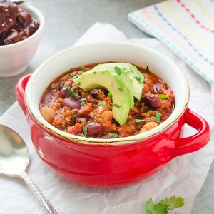 vegan quinoa chili in bowl with avocado on top
