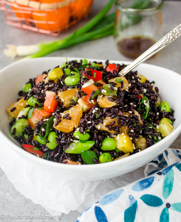 angled overhead view of black rice salad in white bowl with spoon