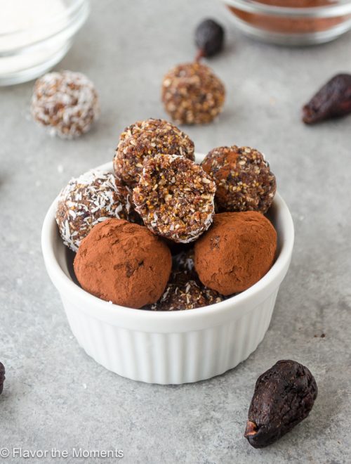 Fig Almond Energy Bite Truffles piled in white ramekin with bite out of top truffle