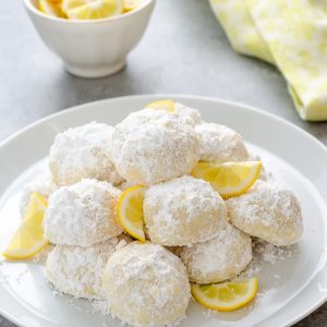Meyer lemon Greek butter cookies or  kourabiedes on white plate with lemon slices