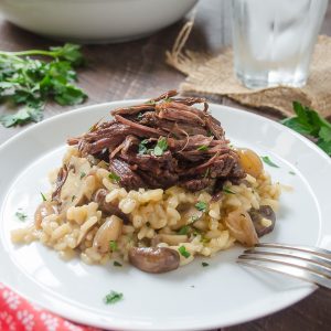 Beef short ribs with mushroom risotto on a white plate