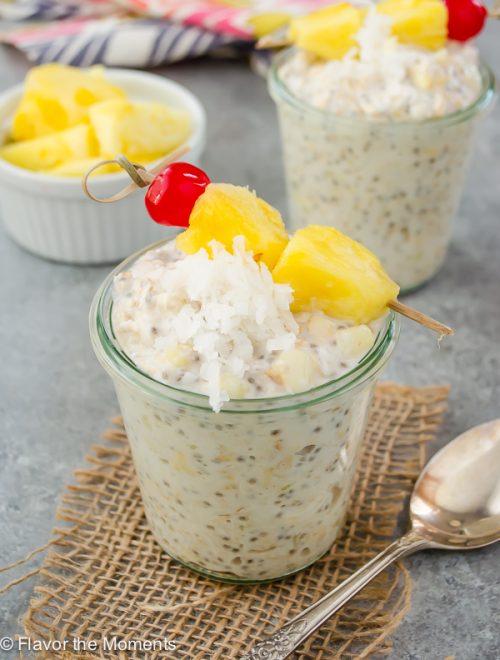 front view of pina colada overnight oats in jar with pinepple, coconut and cherry on top