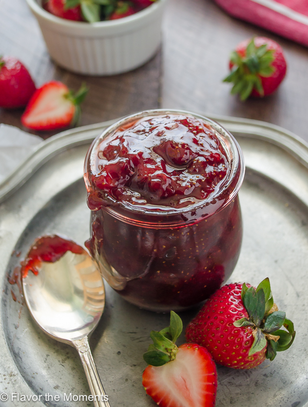 small batch strawberry jam in jar with berries alongside