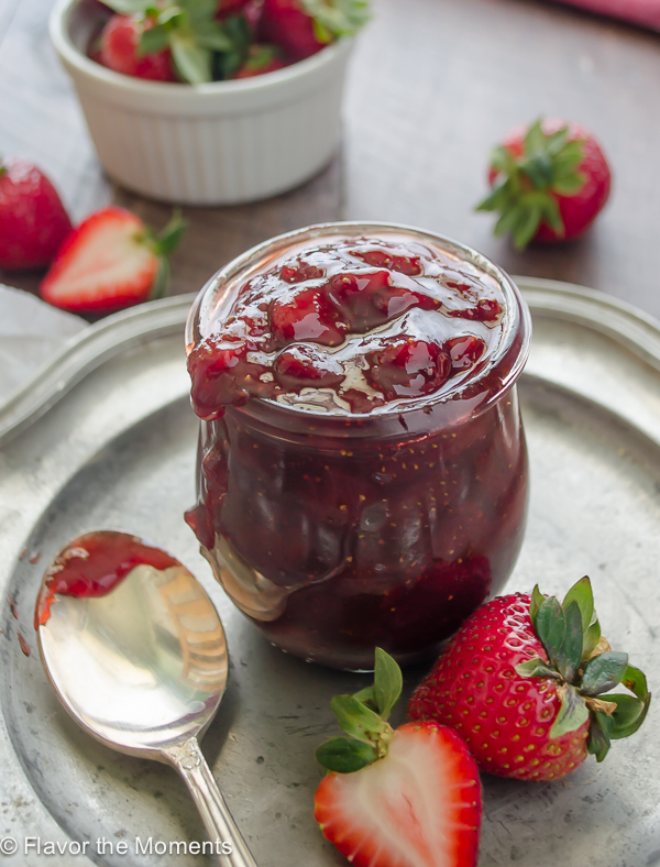 close up of strawberry jam in jar on a silver plate