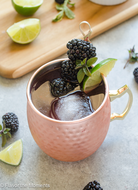 close up of blackberry moscow mule garnished with blackberries and lime