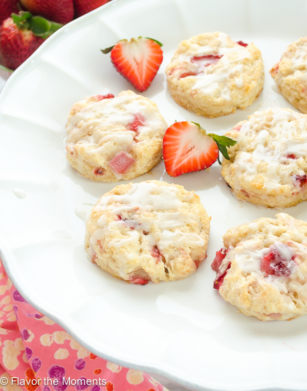 front shot of strawberry scones on white cake stand with halved strawberries