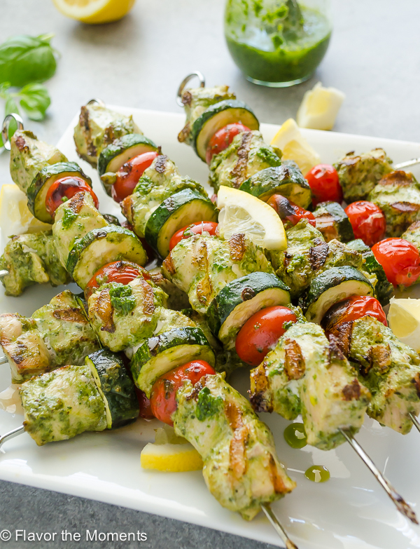 front shot of grilled pesto chicken kebabs on white serving plate