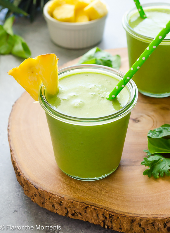 Power green smoothie in jars with pineapple on rim and green straw