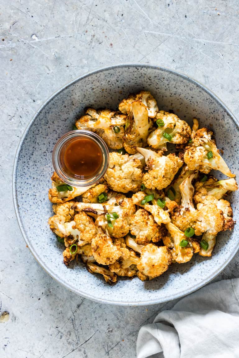 Air fryer buffalo cauliflower wings in a bowl with sauce