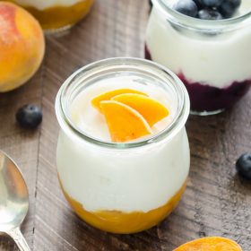 Close up of fruit on the bottom yogurt in jar with peaches on top