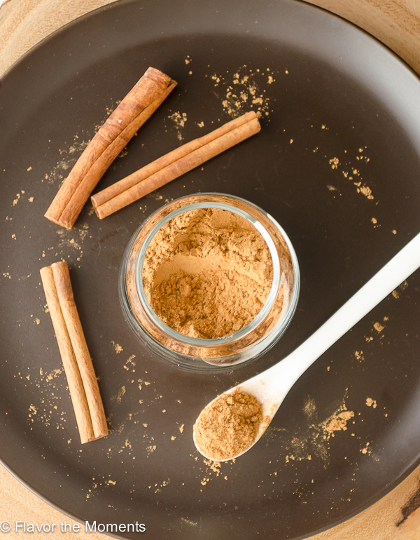 Homemade Chai Spice in a jar with cinnamon sticks and spoon
