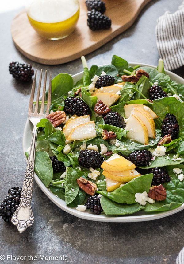 front shot of power greens salad with fork and dressing behind