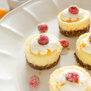 close up of cranberry orange cheesecake with sugared cranberry on top