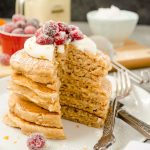eggnog pancakes stacked up with whipped cream and cranberries