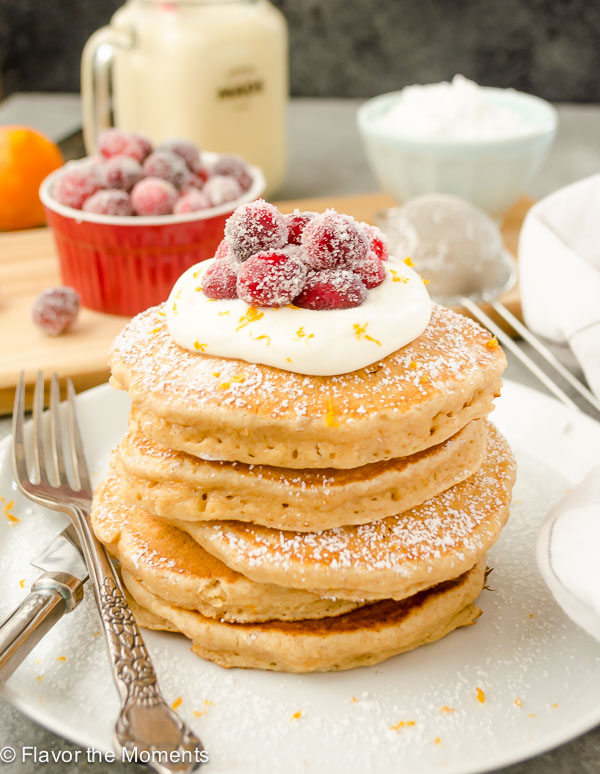 stack of eggnog pancakes with whipped cream and sugared cranberries