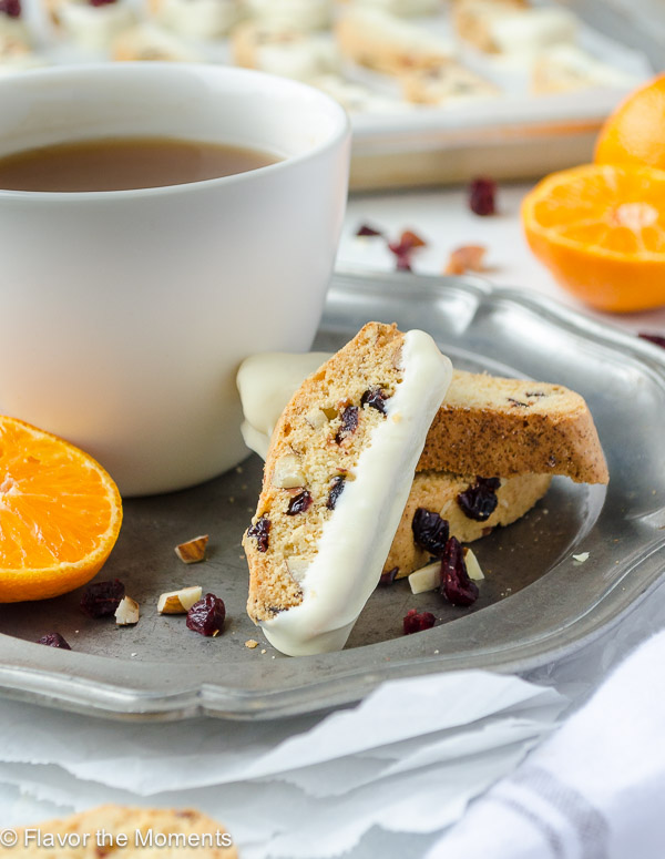 Cranberry Orange Almond Biscotti are crunchy biscotti studded with tart sweet cranberries, toasted almonds, and orange zest. They're dipped in white chocolate and are perfect for tea dunking! @FlavortheMoment