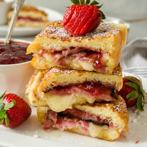Monte cristo french toast stacked on a plate with strawberry on top