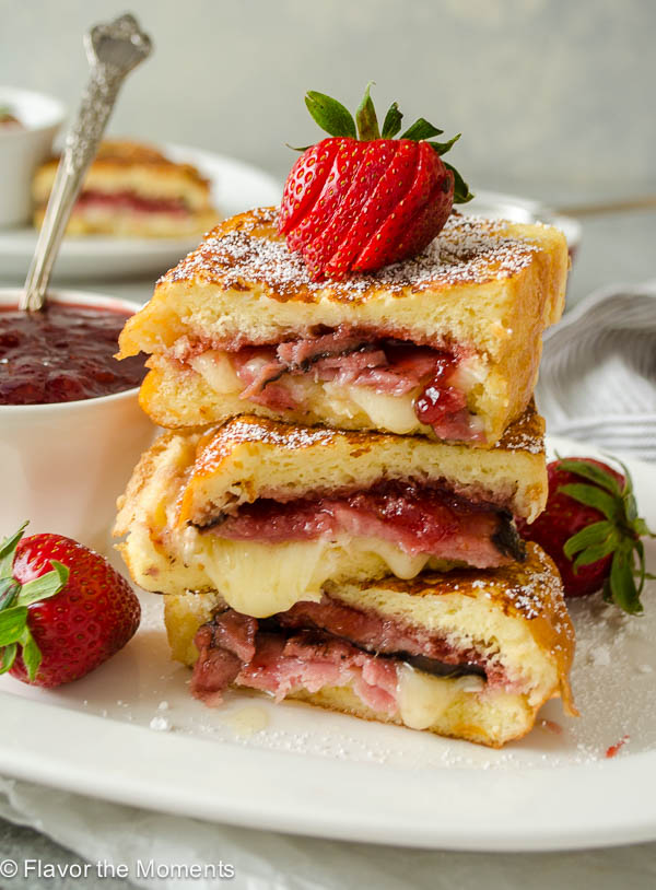 Monte cristo french toast stacked on a plate with strawberry on top