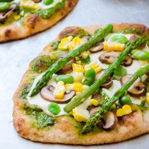 Pesto veggie pizza on baking sheet