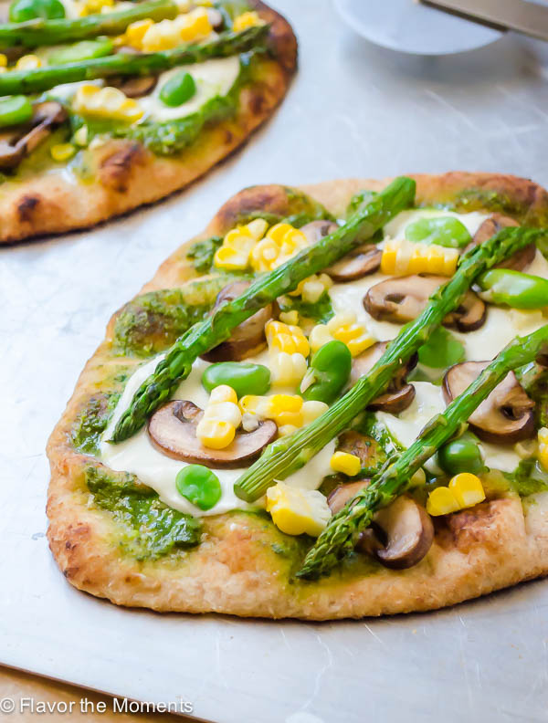 Pesto veggie pizza on baking sheet