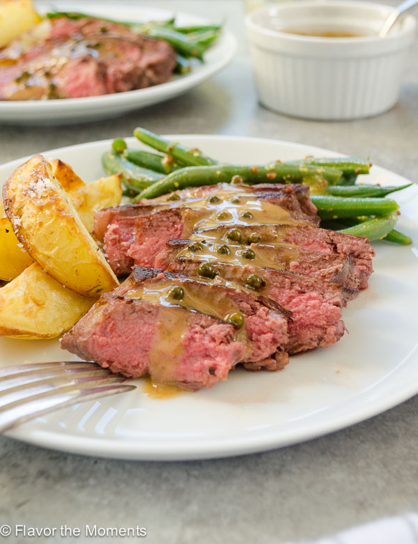 Seared steaks sliced on a plate with peppercorn sauce