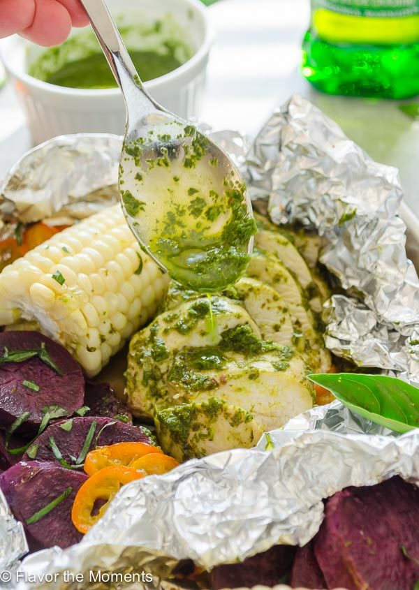 Pesto sauce drizzling over chicken foil packets