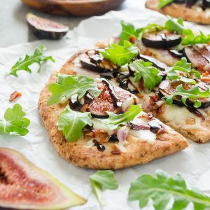 Fig pizza sliced with arugula and balsamic glaze on top