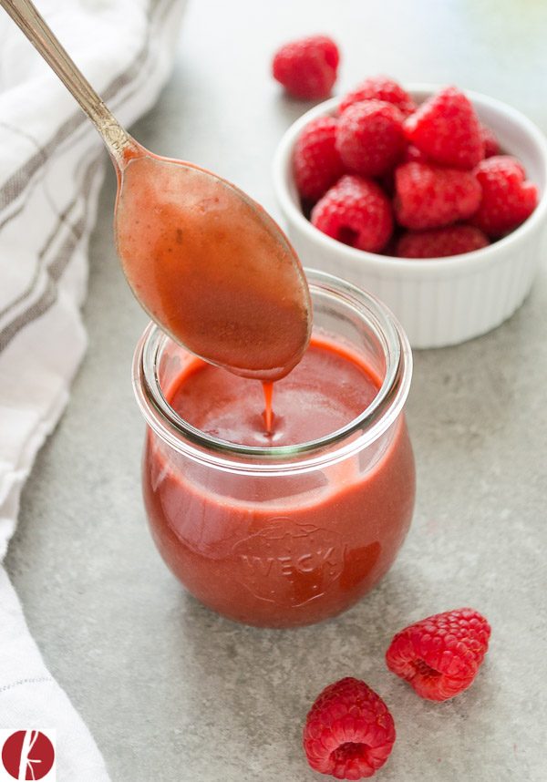 Spoon drizzling raspberry balsamic vinegar dressing into a jar