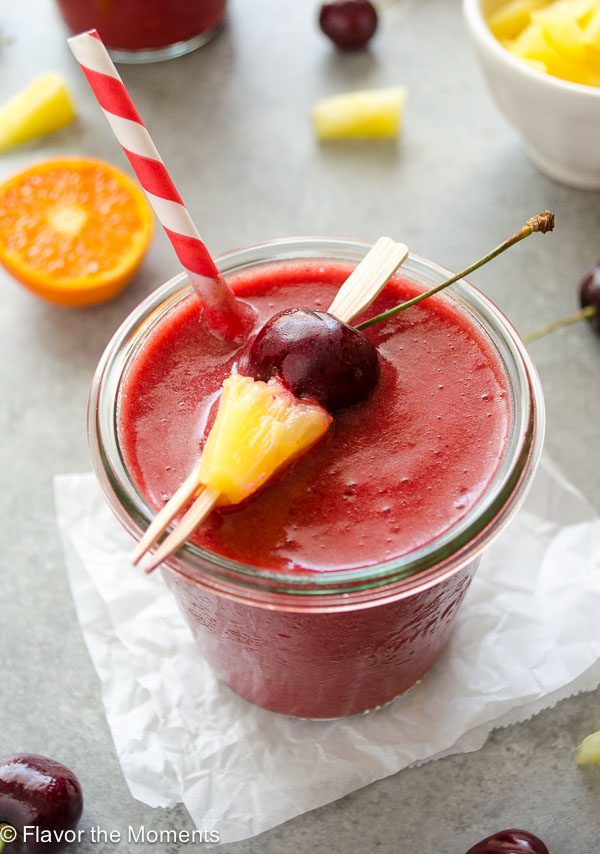 Close up of cherry pineapple smoothie in jar with straw