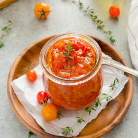 Cherry tomato jam in jar with thyme on top