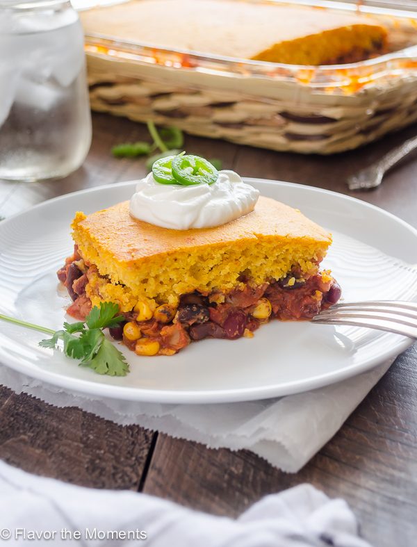 tamale pie on a plate with sour cream and jalapeño on top
