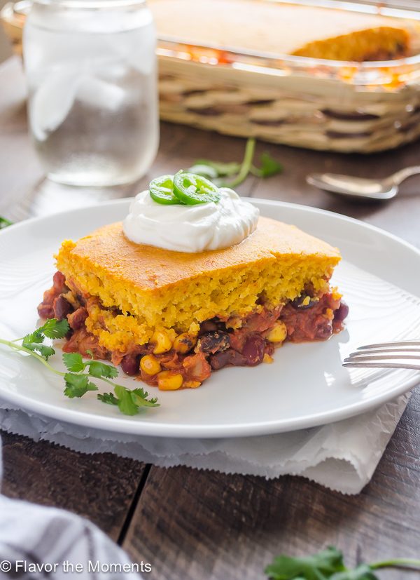 vegetarian tamale pie on a white plate with sour cream and jalapeño