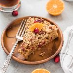 Cranberry coffee cake on a plate with cranberry and orange on top