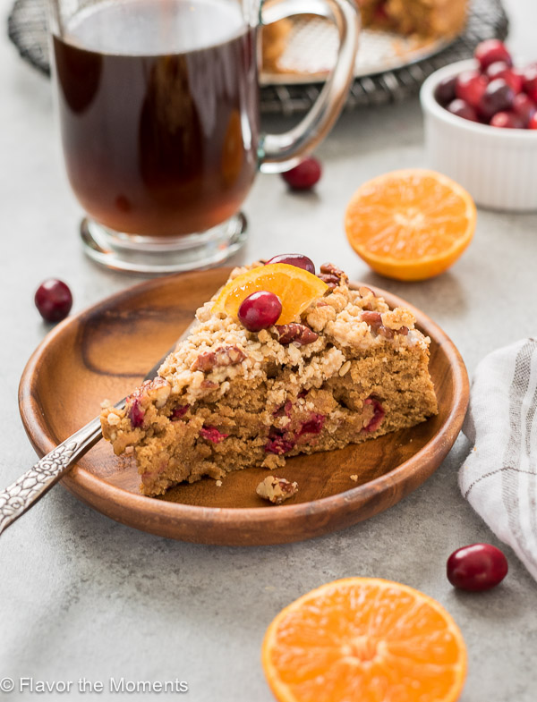 Slice of cranberry coffee cake with orange slice and coffee