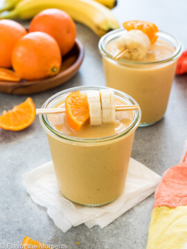 Orange cream smoothie in a jar with orange and banana skewered on a toothpick