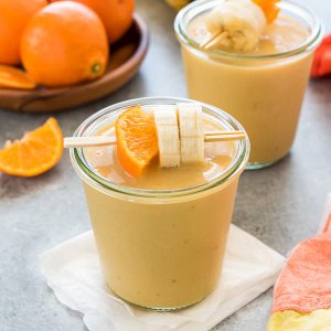 Orange cream smoothie in a jar with orange and banana skewered on a toothpick