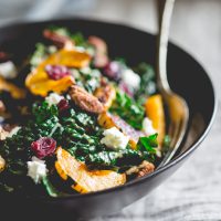 Kale salad with roasted delicata squash in a bowl with spoon