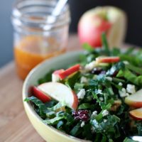 Kale and chard salad in bowl with apple slices on top