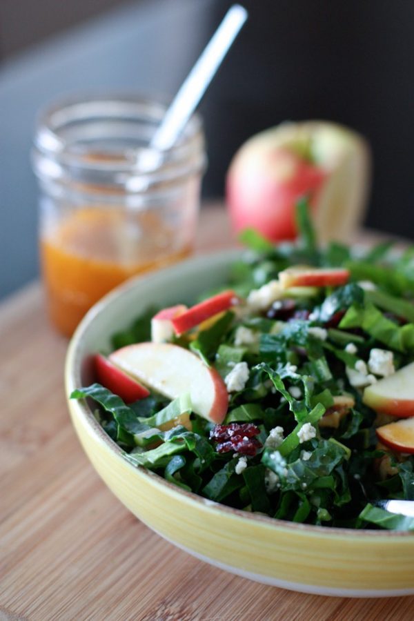 Kale and chard salad in bowl with apple slices on top